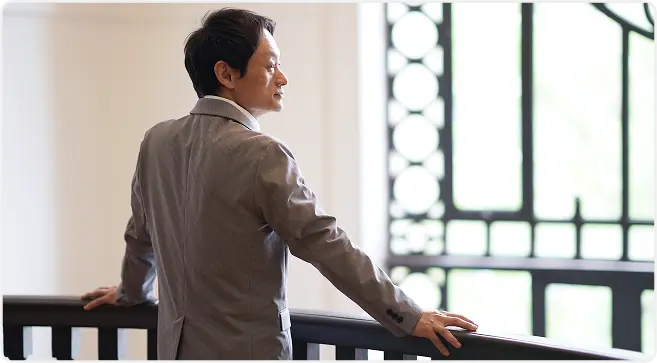 窓の外を見つめるスーツ姿の男性