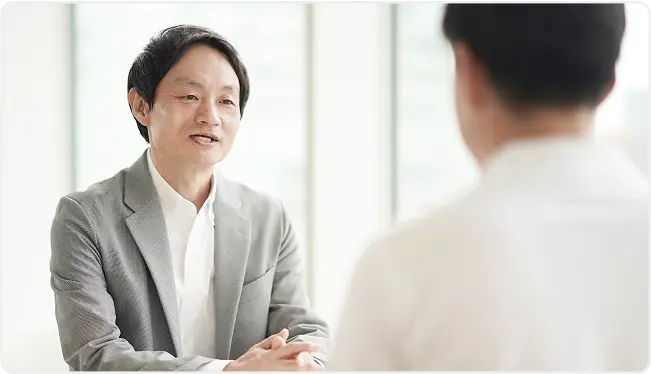 白い室内で相談中の男性が笑顔で話している様子