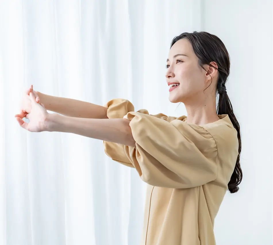 室内で笑顔でストレッチをする女性の横顔、リラックスとセルフケアのイメージ
