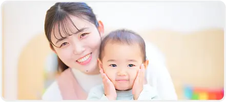 幼児と笑顔で写る若い保育士の女性