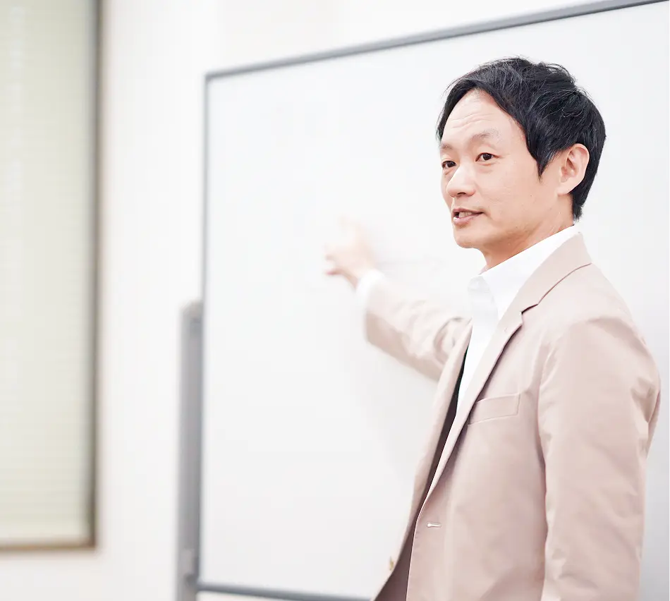ホワイトボードを指差しながら説明する男性講師