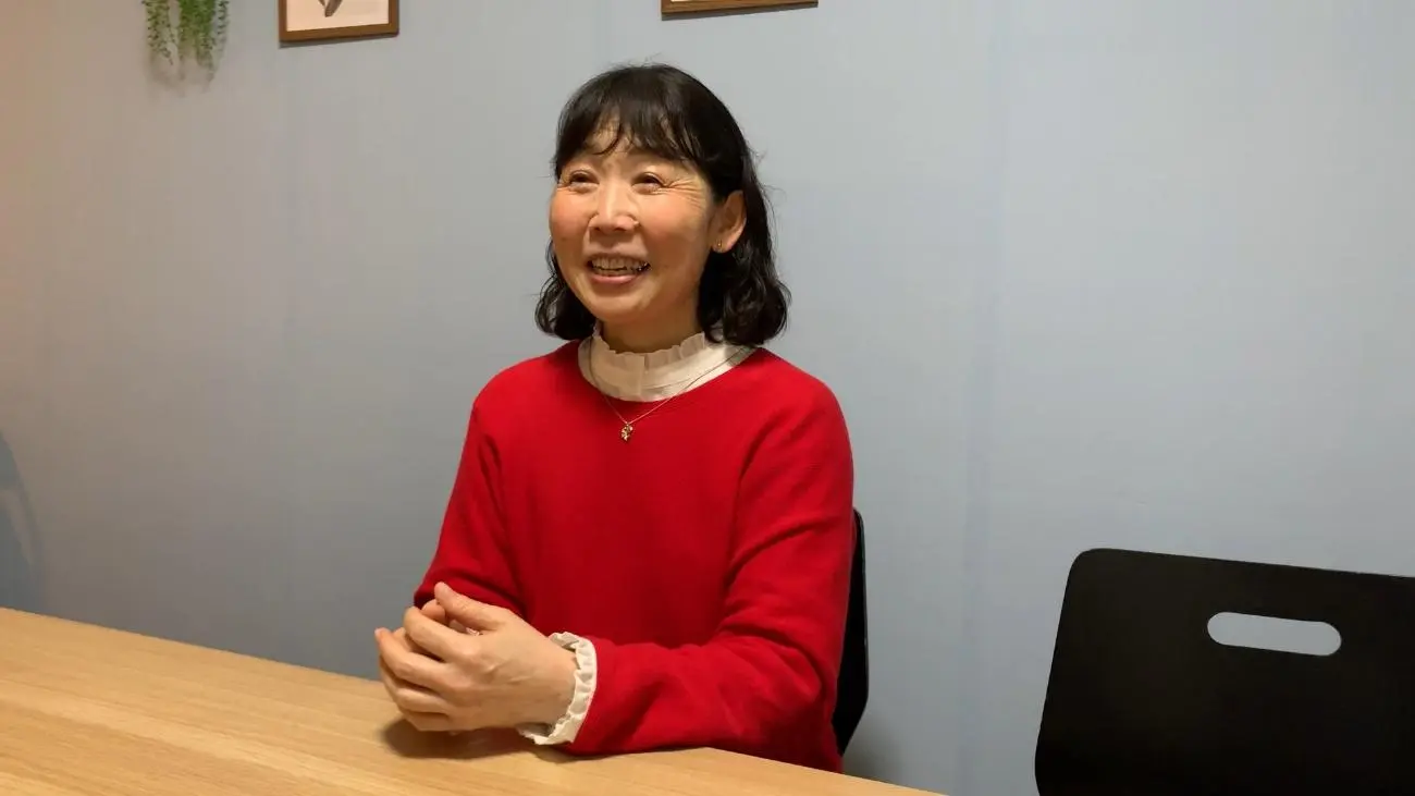 赤い服を着た女性スタッフが笑顔で話している様子